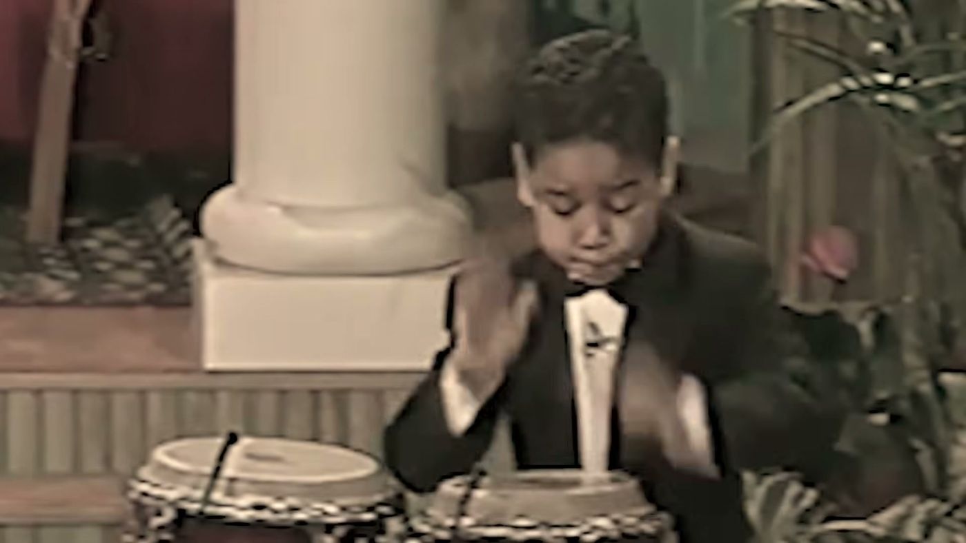 Franco de niño tocando la conga con esmoquin